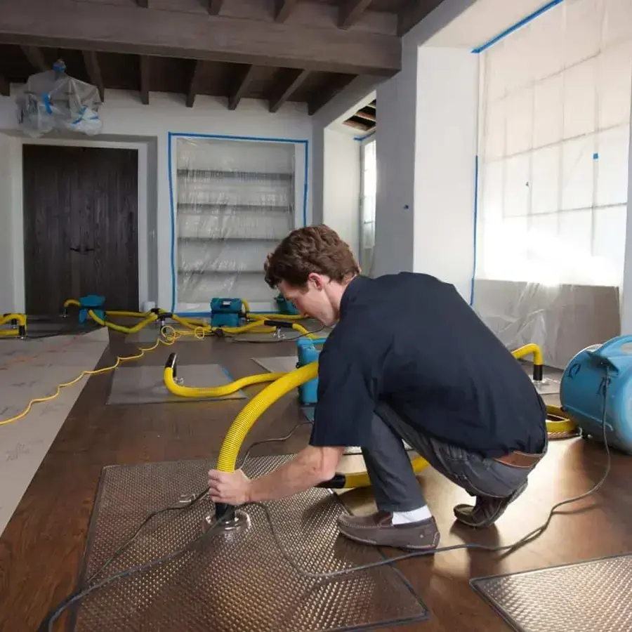 Technician placing a drying mat on a hardwood floor after a water loss