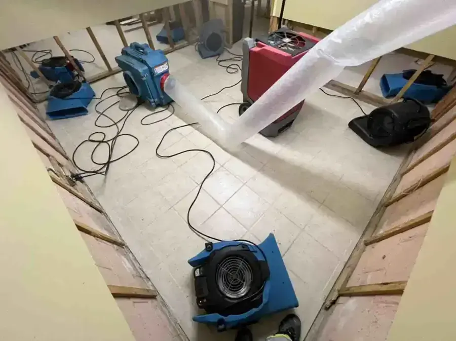 Air movers and layflat duct on tile in a gutted room during a Mineola, NY water damage job