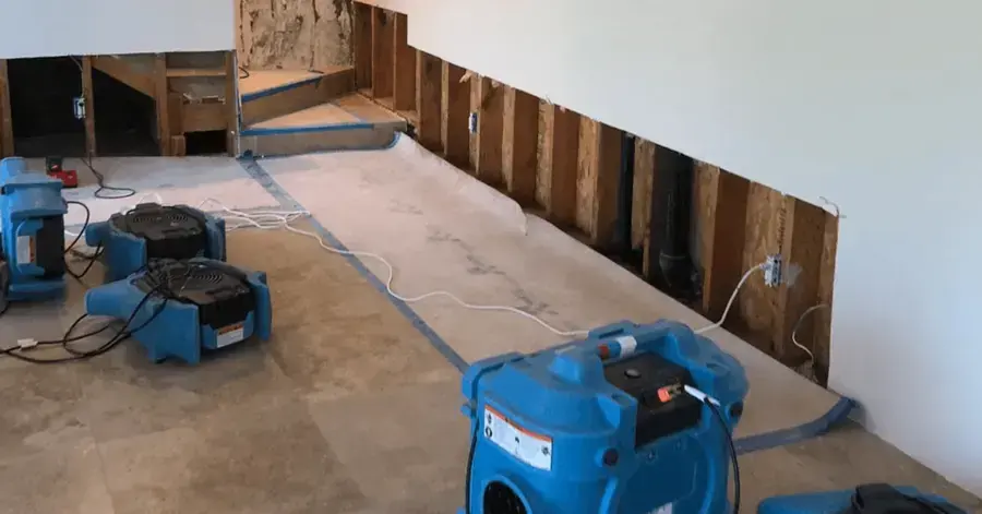 Air movers lined along a wall with the baseboards removed during a Rockville Centre drying job
