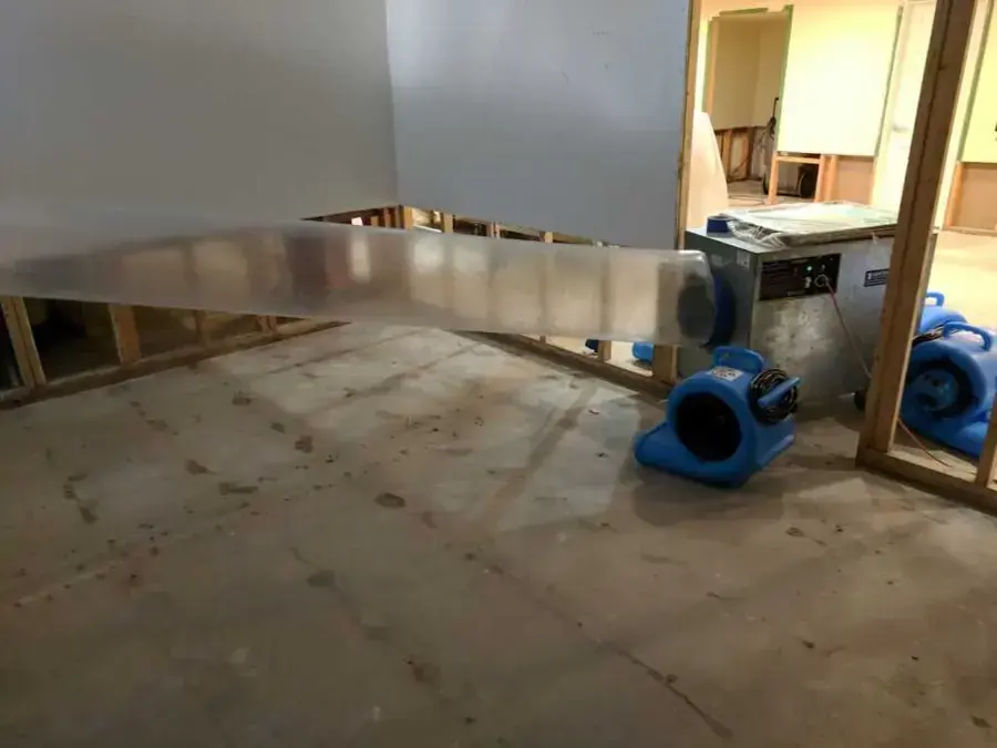 Air movers and a dehumidifier drying a gutted kitchen during a water damage job in Mineola, NY
