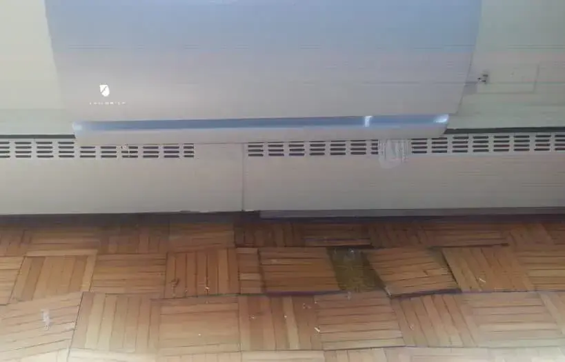 Buckled parquet floor below a baseboard heating unit after a hot water heating leak