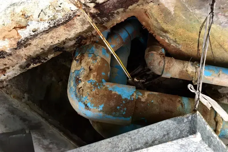 Corroded galvanized and copper pipe exposed under a floor after a pipe failure
