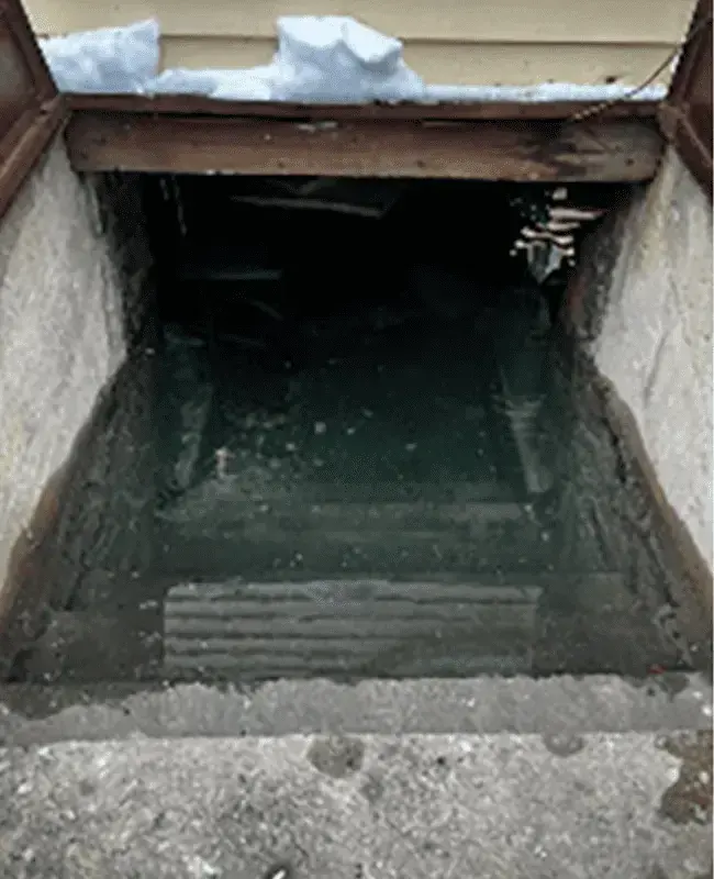 Floodwater standing deep in a below-grade opening after a heavy storm