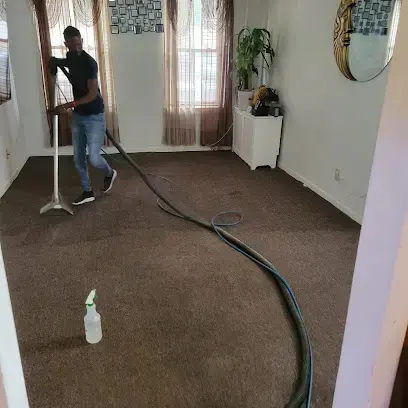Technician running an extraction wand across a soaked living room carpet during water extraction in Hempstead, NY